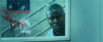Movie still from “Central Intelligence” (2016), directed by Rawson Marshall Thurber – A man looking out a window through a wire fence; Close Up shot, Over the shoulder angle