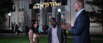 Movie still from “Central Intelligence” (2016), directed by Rawson Marshall Thurber – A man and a woman standing next to each other in front of a building; Medium shot, Over the shoulder angle