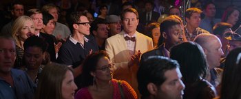 Movie still from “Central Intelligence” (2016), directed by Rawson Marshall Thurber – A crowd of people standing around a room; Medium shot, Over the shoulder angle