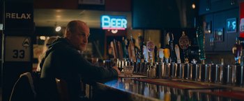 Movie still from “Champions” (2023), directed by Bobby Farrelly – A man sitting at the bar of a bar; Medium shot, Over the shoulder angle