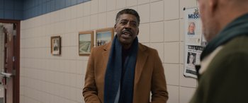 Movie still from “Champions” (2023), directed by Bobby Farrelly – An older man wearing a brown coat and a blue scarf; Medium shot, Over the shoulder angle