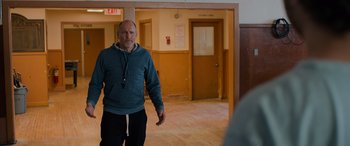 Movie still from “Champions” (2023), directed by Bobby Farrelly – A man standing in a room next to a door way; Medium shot, Over the shoulder angle