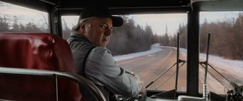 Movie still from “Champions” (2023), directed by Bobby Farrelly – A man sitting in the driver's seat of a bus; Medium shot, Over the shoulder angle