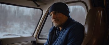 Movie still from “Champions” (2023), directed by Bobby Farrelly – A man in a blue jacket and a blue hat is sitting in a car; Close Up shot, Low angle