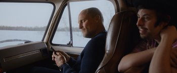 Movie still from “Champions” (2023), directed by Bobby Farrelly – A man sitting in the driver's seat of a car looking at his cell phone; Medium shot, Low angle