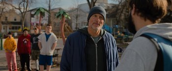 Movie still from “Champions” (2023), directed by Bobby Farrelly – An older man wearing a blue jacket and a blue hat; Medium shot, Over the shoulder angle