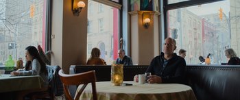 Movie still from “Champions” (2023), directed by Bobby Farrelly – A man sitting at a table in a restaurant; Wide shot, Low angle