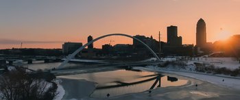 Movie still from “Champions” (2023), directed by Bobby Farrelly – A view of a bridge over a body of water at sunset; Extreme Wide shot, High angle
