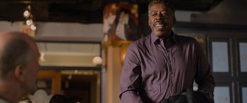 Movie still from “Champions” (2023), directed by Bobby Farrelly – An older man standing in front of a painting; Medium shot, Low angle