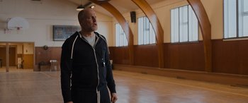 Movie still from “Champions” (2023), directed by Bobby Farrelly – A man standing in an empty room looking up at the ceiling; Medium shot, Low angle