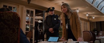 Movie still from “Champions” (2023), directed by Bobby Farrelly – A police officer standing next to a woman in front of a laptop; Medium shot, Over the shoulder angle