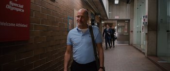 Movie still from “Champions” (2023), directed by Bobby Farrelly – A man in a blue shirt is walking down a hallway; Medium shot, Low angle