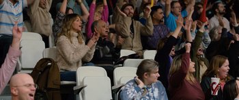 Movie still from “Champions” (2023), directed by Bobby Farrelly – A group of people sitting in a stadium watching a game; Medium shot, Low angle