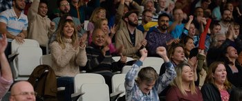 Movie still from “Champions” (2023), directed by Bobby Farrelly – A group of people sitting and standing in a stadium; Medium shot, High angle