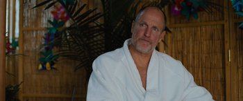 Movie still from “Champions” (2023), directed by Bobby Farrelly – A man in a white bathrobe sitting in front of a palm tree; Close Up shot, Over the shoulder angle