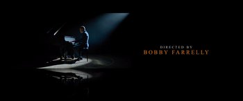 Movie still from “Champions” (2023), directed by Bobby Farrelly – A person sitting in a chair in a dark room; Extreme Wide shot, High angle