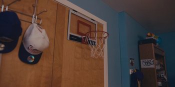 Movie still from “Chang Can Dunk” (2023), directed by Jingyi Shao – A basketball hoop hanging on the wall in a room; Medium shot, Low angle