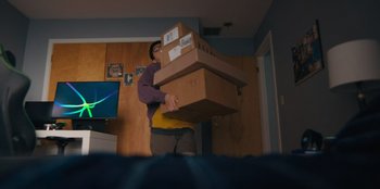 Movie still from “Chang Can Dunk” (2023), directed by Jingyi Shao – A man holding a box in a room; Wide shot, Low angle
