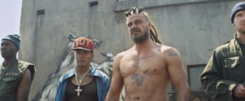 Movie still from “Chappie” (2015), directed by Neill Blomkamp – A man with long hair and a beard is wearing a crown; Medium shot, Low angle