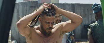 Movie still from “Chappie” (2015), directed by Neill Blomkamp – A man with a bunch of dreads on his head; Close Up shot, Over the shoulder angle