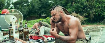 Movie still from “Chappie” (2015), directed by Neill Blomkamp – A man with dreadlocks is talking on a cell phone; Close Up shot, Low angle