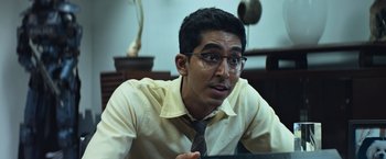 Movie still from “Chappie” (2015), directed by Neill Blomkamp – A man wearing glasses and a yellow shirt; Close Up shot, Over the shoulder angle