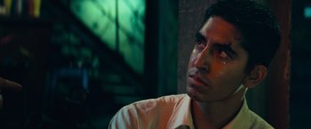 Movie still from “Chappie” (2015), directed by Neill Blomkamp – A person sitting down with his eyes wide open; Close Up shot, Low angle