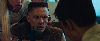 Movie still from “Chappie” (2015), directed by Neill Blomkamp – A man with red hair is looking into a mirror; Close Up shot, Over the shoulder angle