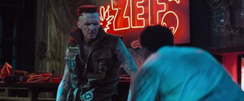 Movie still from “Chappie” (2015), directed by Neill Blomkamp – A man with a red mohawk is standing in front of a neon sign; Close Up shot, Over the shoulder angle