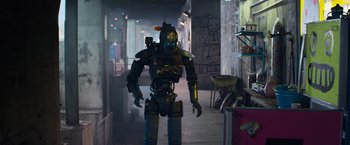 Movie still from “Chappie” (2015), directed by Neill Blomkamp – A robot is standing in the middle of a hallway; Wide shot, Low angle