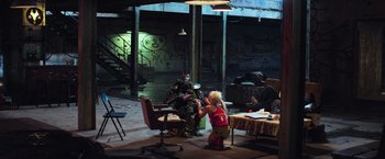 Movie still from “Chappie” (2015), directed by Neill Blomkamp – A woman in a pink shirt and yellow pants painting a robot; Wide shot, High angle