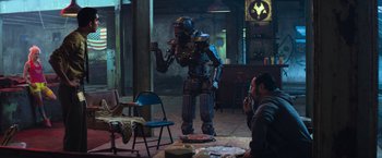 Movie still from “Chappie” (2015), directed by Neill Blomkamp – A man sitting in front of an iron man statue; Wide shot, Over the shoulder angle