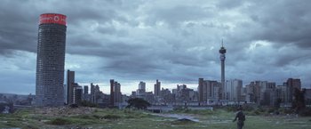 Movie still from “Chappie” (2015), directed by Neill Blomkamp – A view of a city skyline with a cloudy sky; Extreme Wide shot, Low angle