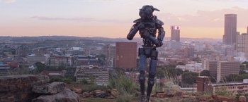 Movie still from “Chappie” (2015), directed by Neill Blomkamp – A robot statue on top of a hill overlooking a city; Wide shot, Low angle