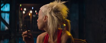 Movie still from “Chappie” (2015), directed by Neill Blomkamp – A woman with a mohawk hair style is looking to the side; Close Up shot, Over the shoulder angle