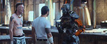 Movie still from “Chappie” (2015), directed by Neill Blomkamp – A man standing in front of a robot with a sword; Wide shot, Low angle