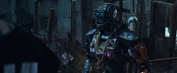 Movie still from “Chappie” (2015), directed by Neill Blomkamp – A robot with a chain around it's neck; Medium shot, Low angle