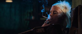 Movie still from “Chappie” (2015), directed by Neill Blomkamp – A woman is smoking a cigarette in a dark room; Close Up shot, Low angle