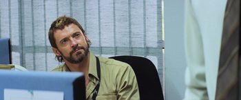 Movie still from “Chappie” (2015), directed by Neill Blomkamp – A man sitting at a computer desk with a headset on; Close Up shot, Over the shoulder angle