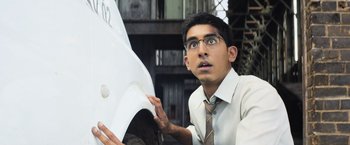 Movie still from “Chappie” (2015), directed by Neill Blomkamp – A man in a white dress shirt and tie looking at a white car; Close Up shot, Low angle