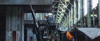 Movie still from “Chappie” (2015), directed by Neill Blomkamp – A man in a robot costume holding a gun; Medium shot, Low angle