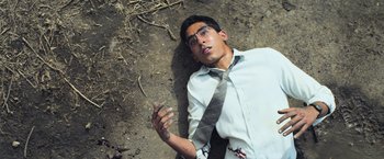 Movie still from “Chappie” (2015), directed by Neill Blomkamp – A man laying on the ground smoking a cigarette; Medium shot, Overhead angle