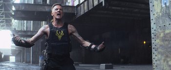 Movie still from “Chappie” (2015), directed by Neill Blomkamp – A man in black shirt and black vest holding a gun; Medium shot, Low angle