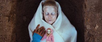 Movie still from “Chappie” (2015), directed by Neill Blomkamp – A person with a doll in a blanket; Close Up shot, Overhead angle