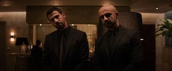 Movie still from “Charlie's Angels” (2019), directed by Elizabeth Banks – A couple of men standing next to each other in a room; Medium shot, Low angle