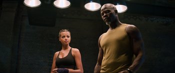 Movie still from “Charlie's Angels” (2019), directed by Elizabeth Banks – A man and a woman standing next to each other in front of lights; Medium shot, Low angle