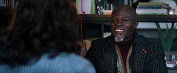 Movie still from “Charlie's Angels” (2019), directed by Elizabeth Banks – A man smiling at a woman in front of a book shelf; Close Up shot, Over the shoulder angle