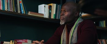 Movie still from “Charlie's Angels” (2019), directed by Elizabeth Banks – A man sitting in front of a book shelf; Close Up shot, Low angle