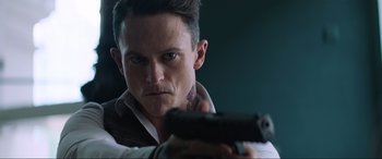 Movie still from “Charlie's Angels” (2019), directed by Elizabeth Banks – A man is holding a gun in his hand; Close Up shot, Low angle