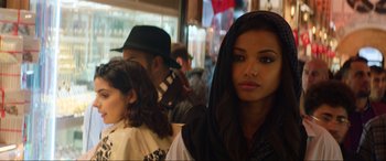 Movie still from “Charlie's Angels” (2019), directed by Elizabeth Banks – A woman in a black hooded jacket standing in front of other people; Close Up shot, Over the shoulder angle